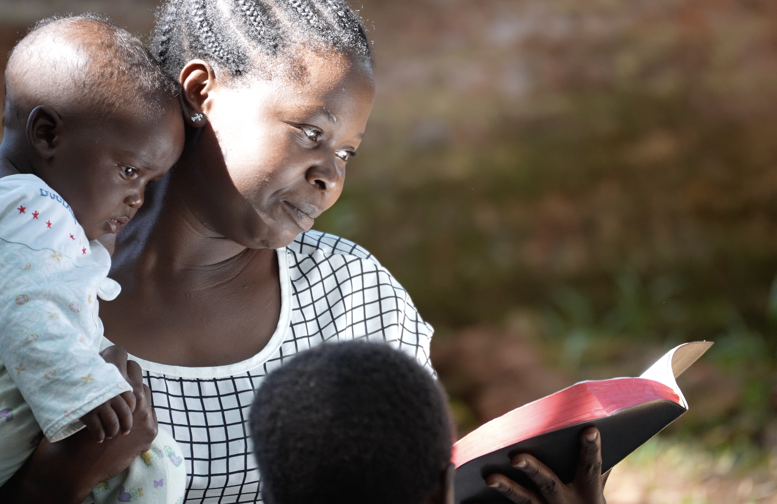 A woman reading the Bible with children in Malawi